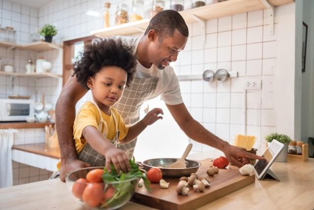 A man cooks dinner with his son